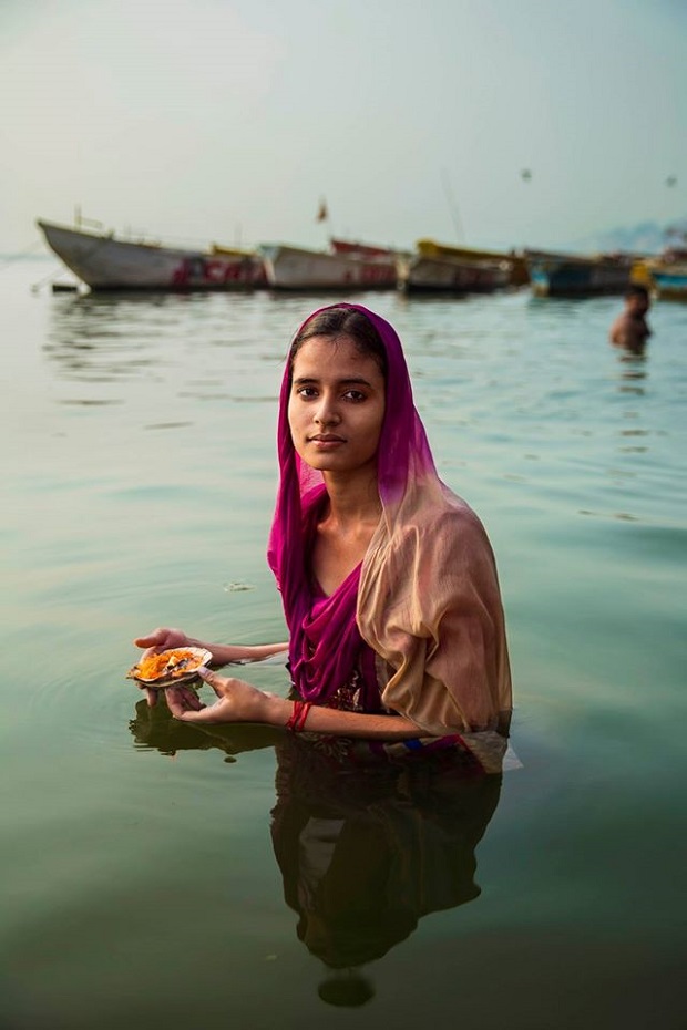Hindu pilgrim making an offering on the Ganges River, Varanasi, India.
